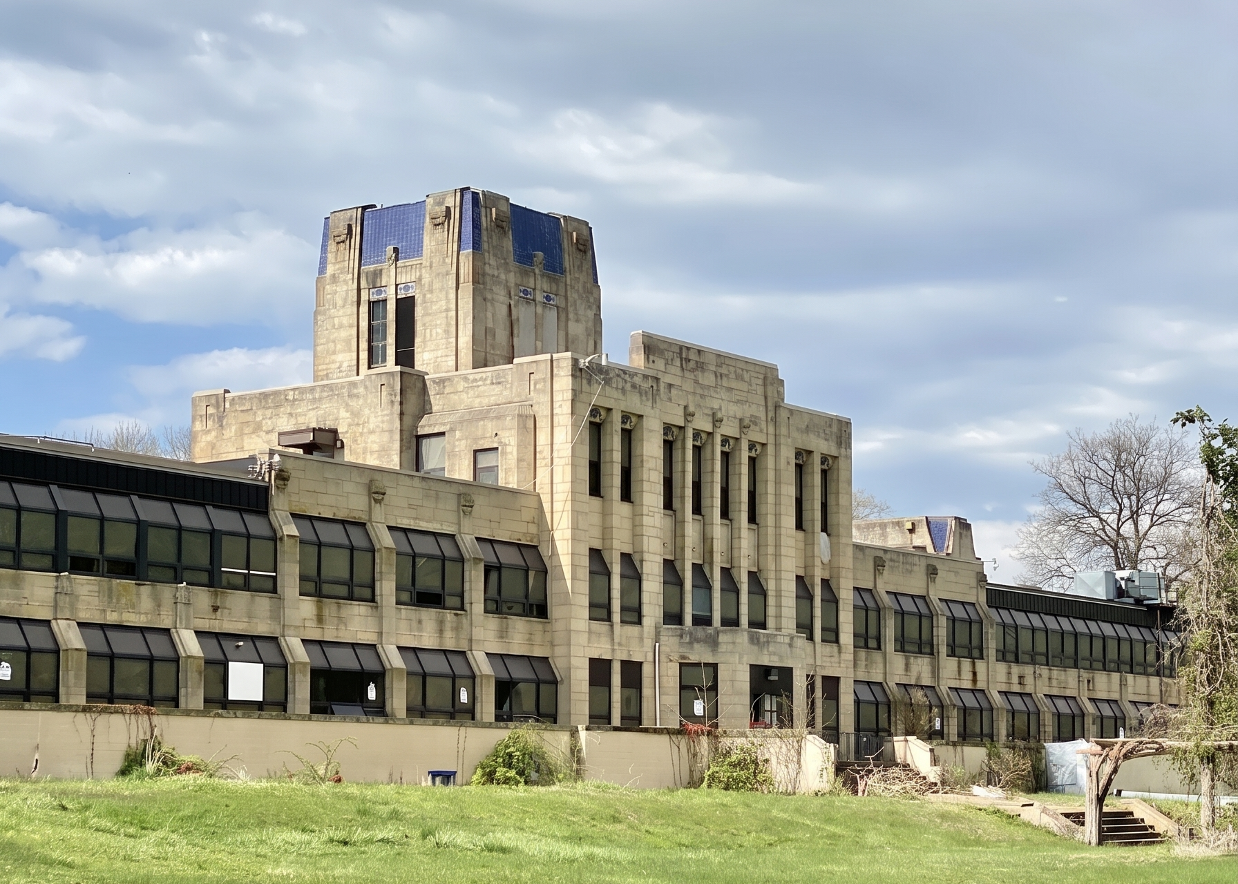 Historic art deco style building against cloudy sky and green lawn
